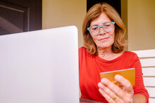 Senior Woman Holding Credit Card Doing Online Shopping At Front Porch