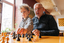 Son Playing Chess With Grandfather At Club
