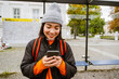 © Drobot Dean - Cheerful asian woman using smartphone while standing at bus station