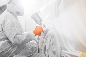 Wall Mural - Male worker with mask and protective clothes painting car using spray compressor.