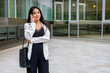 © Clàudia Ayuso - Close up portrait of a young executive businesswoman in urban outdoors calling with a smartphone. Smiling empowered woman dressed smart casual outside the office work site. Horizontal with copy space.