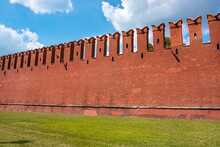 The Famous Kremlin Wall With Dovetail Crenellations. The Texture Of The Red Ancient Brick Kremlin Wall