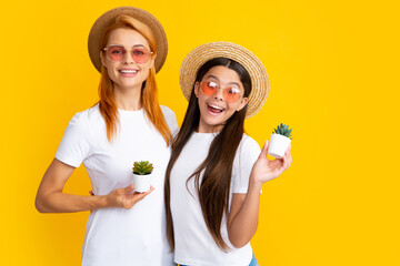 Sticker - Excited amazed mother and daughter in straw hat and sunglasses with potted plant on yellow background.