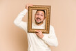 © Asier - Adult latin man holding a vintage frame and smiling isolated