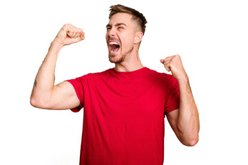 Young caucasian man cut out isolated raising fist after a victory, winner concept.