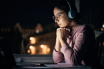 Laptop, night and music with a student woman in her home for learning, education or development using the internet. Computer, research and elearning with a female pupil studying late in a dark house