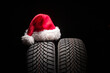 Car tire service and christmas hat on black background with copy space for text