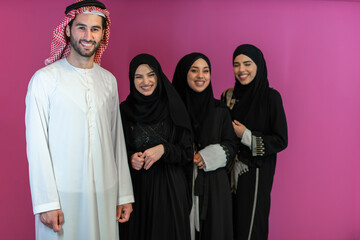 Wall Mural - Group portrait of young Muslim people Arabian men with three Muslim women in a fashionable dress with hijab isolated on a pink background