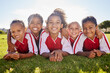 © Nina/peopleimages.com - Girl, soccer group portrait and lying with smile, team building happiness or solidarity to relax at training. Female kids, sports diversity and happy with friends, teamwork or development in football