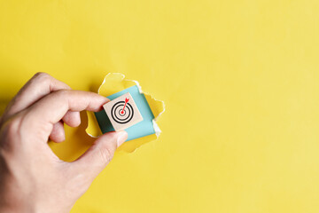 Aufkleber - Dartboard with arrow hiding of yellow punched paper, hand picking cube block with dart icon target for planning business objective target to successful development, innovation, idea, creative.