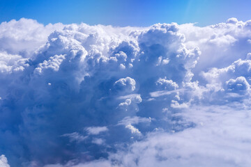 Wall Mural - White cloud on blue sky. See through the plane window in sunny weather bird's eye view.