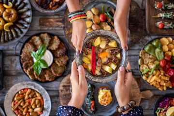 Wall Mural - Meat stew with vegetables at the hands of two women. Orman kebabı .