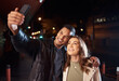 © D Lahoud/peopleimages.com - Couple of friends, phone or night selfie on city street or road for social media, profile picture or birthday celebration vlog. Smile, happy or influencer people bonding in dark while live streaming