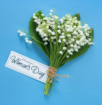 Wall Mural - happy women's day card with white bells on a blue background, spring flowers bouquet, free space
