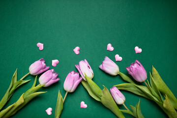 Wall Mural - festive mockup frame with pink tulips and hearts on a dark green background. copy space. top view. flat lay. concept of mother's day, valentines day, eighth of march