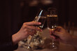 Two glasses with sparkling champagne wine in hands, concept for holiday, bokeh, in a restaurant. Romantic dinner. Man and woman are holding glasses of champagne. Concept for Valentine's day or date