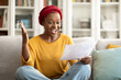 Happy young black woman sit on couch reading good news