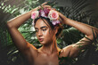 © Allistair F/peopleimages.com - Beauty, forest and face of a woman with a flower crown standing by a tropical leaf background. Cosmetics, skincare and model from Mexico with a wellness skin routine with green plants in nature.
