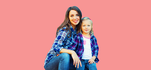 Portrait of stylish smiling mother and child girl on pink background