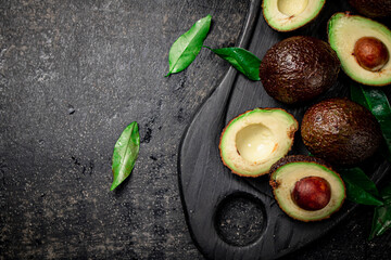 Poster - Fresh avocado with foliage on a cutting board.