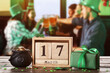 Pot with coins, calendar with date of St. Patrick's Day and gift on table in bar