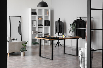 Wall Mural - Interior of modern atelier with tailor's workplace, shelving unit and clothes