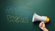 © New Africa - Man calling for Stop War using megaphone, closeup. Words in colors of Ukrainian flag on green chalkboard
