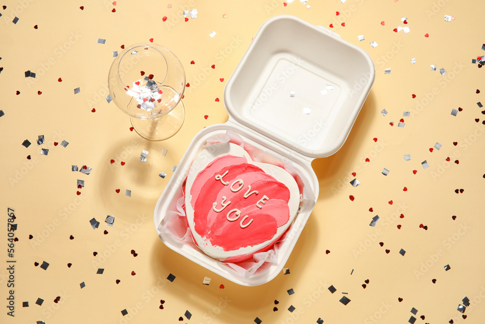 Plastic lunch box with heart-shaped bento cake and glass on beige background. Valentine's Day celebration