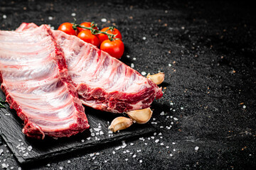 Wall Mural - Raw ribs on a stone board with tomatoes and pieces of salt. 