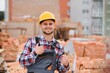 © Serhii - Construction worker man in work clothes and a construction helmet. Portrait of positive male builder in hardhat working at construction site.