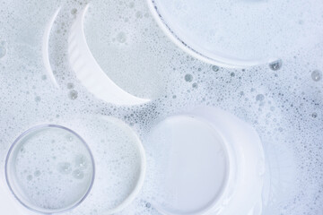 Dishes and bowls in water and bubbles of dishwashing liquid