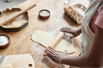 Black woman baking homemade pastry and rolling dough