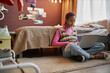 © Seventyfour - Black teenage girl using laptop indoors sitting on floor
