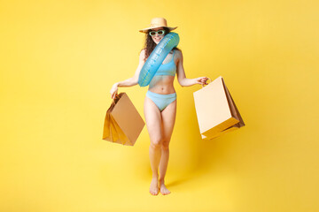 young attractive brunette girl in a blue swimsuit with a swimming inflatable ring holds packages with purchases