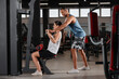 © New Africa - Happy trainer showing woman how to do exercise properly in modern gym