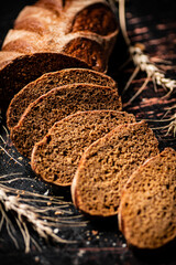 Poster - Slices of fresh bread on the table with spikelets. 