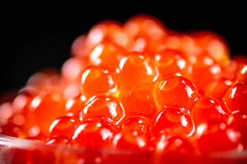 Poster - Grains of red caviar on a black background.