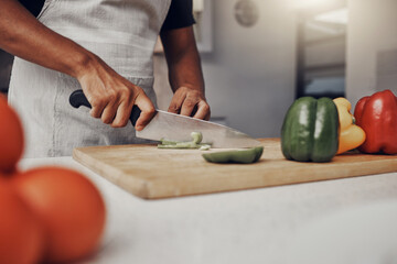 Wall Mural - Hands, food and cooking with a man in the kitchen, cutting a green pepper on a wooden chopping board. Salad, health and diet with a male chef preparing a meal while standing alone in his home