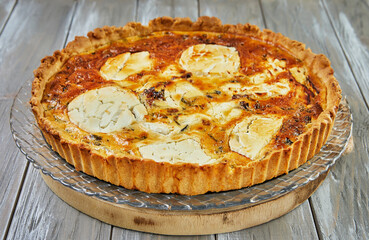 Wall Mural - Goat cheese quiche on a wooden background. French gourmet cuisine