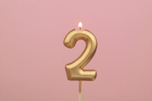 Burning Golden Birthday Candle On Pink Background, Number 2