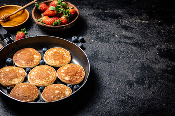 Sticker - Pancakes in a frying pan with fresh berries and honey. 