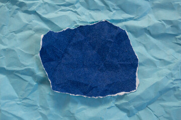 Blank torn paper isolated on blue background. Top view of crumpled blue paper piece with copy space.