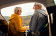 © Zoran Zeremski - Senior couple sitting against the car, resting after hiking in countryside.