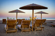 Colorful sky over sunshades with loungers on sandy beach at resort Faliraki in Rhodes island