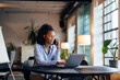 © bnenin - African businesswoman making a phone call while working online, talking to one client.