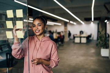 Wall Mural - Portrait of an African businesswoman writing on a glass board.