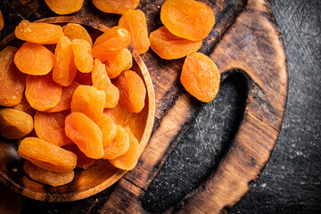 Sticker - Dried apricots in a plate on a cutting board. 