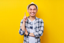 Smart Proactive Young Handsome Ethnic Asian Man 20s Wearing Casual Clothes Hat Pointing Finger Up At A Great New Idea Isolated On Yellow Background Studio Portrait. People Lifestyle Concept
