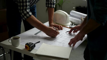 Wall Mural - Two cropped architects discussing floor plan at table in office. Design of the house. Engineer. Tools for drawing. Creating a drawing.