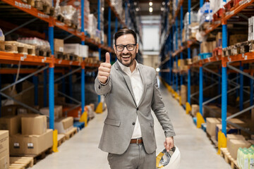 Wall Mural - An executive stands in warehouse and giving thumbs up.